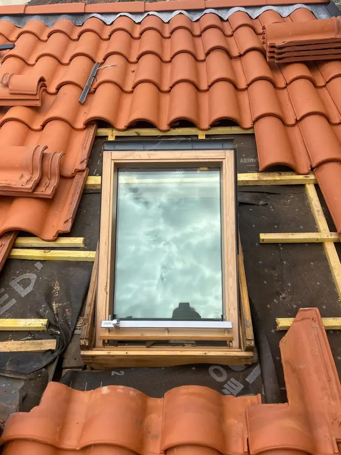 Fenêtre de toit encastrée dans une couverture en tuiles neuves, liteaux apparents