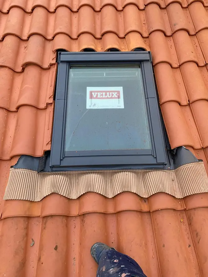 Fenêtre de toit neuve posée dans une couverture en tuiles