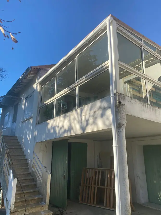 Véranda vitrée à l'étage d'une maison, toiture au-dessus