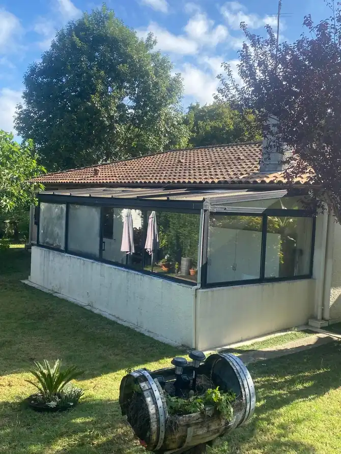 Maison basse et sa véranda vitrée vues du jardin