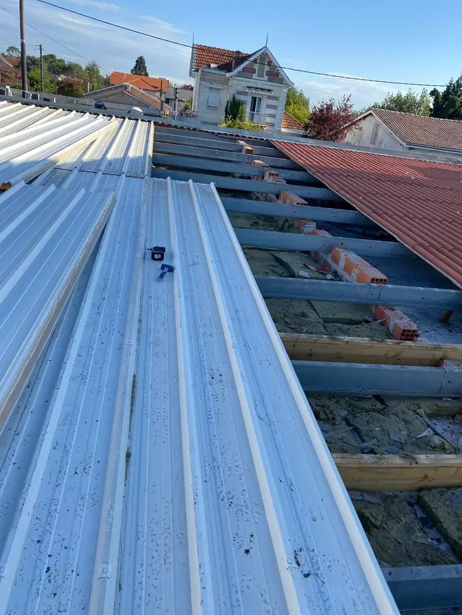 Couverture en bac acier neuve le long d'un rampant en tuiles