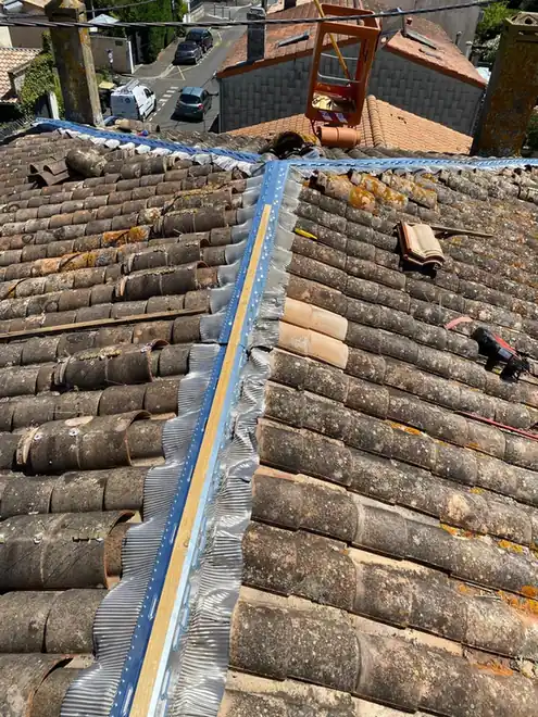 Faîtage en zinc neuf sur une toiture en tuiles patinées