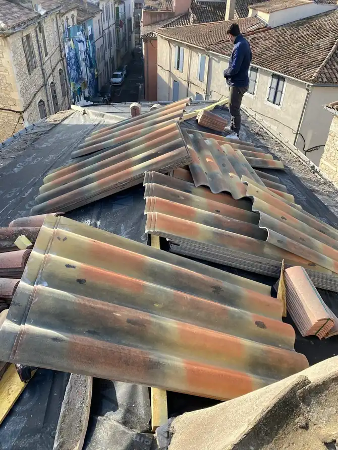 Couvreur debout sur un faîtage, toiture en cours de dépose