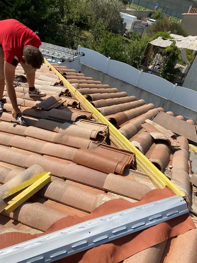 Couvreur posant une rive près de panneaux solaires sur le rampant